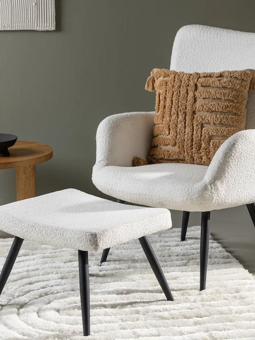 Fauteuil bouclette blanc à pieds fins noirs, vue de face avec repose-pieds