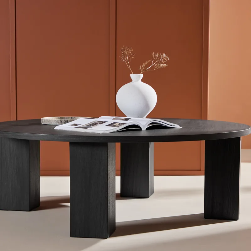 Table basse ronde noire Juno de 120 cm, vue de face : plateau rond sur quatre pieds en blocs