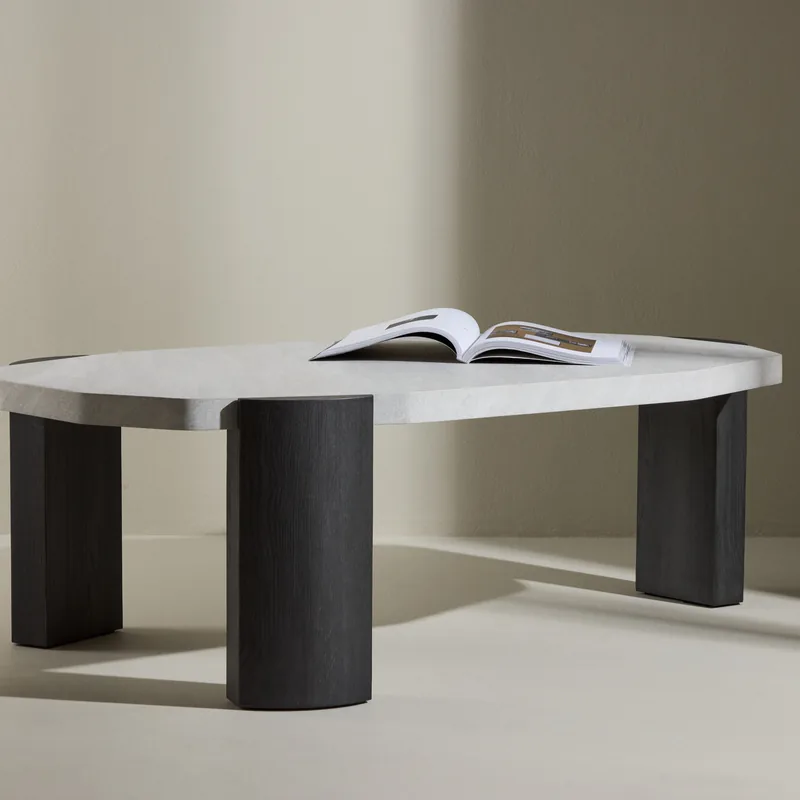 Table basse Kres, plateau effet pierre clair aux bords arrondis sur pieds noirs demi-cylindres, vue de face