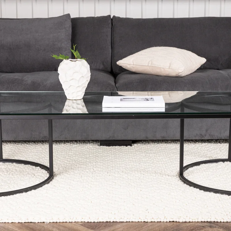 Table basse Skanör, plateau rectangulaire en verre sur pieds en arceaux de métal noir, vue de face