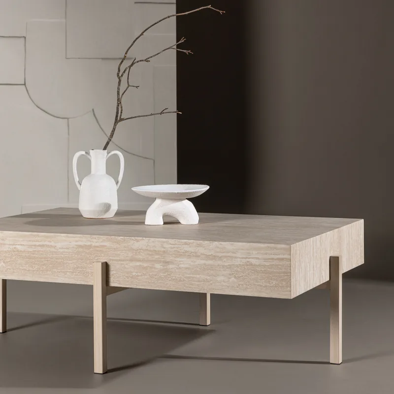 Table basse Vadholmen effet travertin beige sur pieds fins en métal doré, vue de face