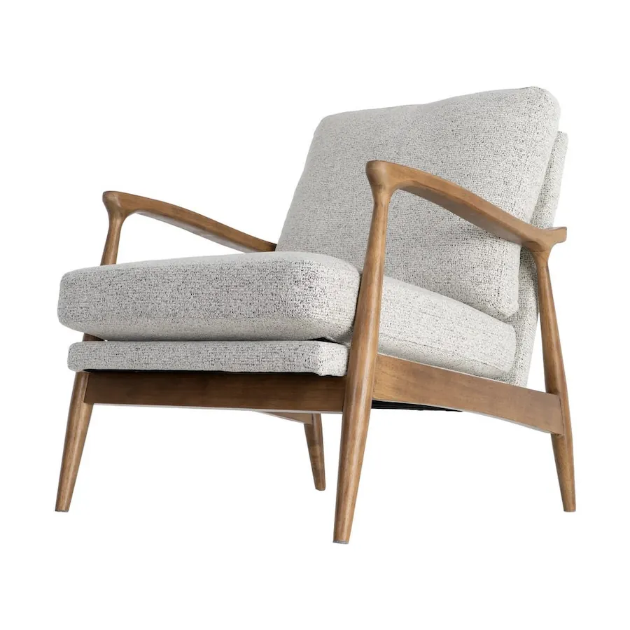 Fauteuil Ixia vu de trois quarts avant, accoudoirs courbes et coussins clairs
