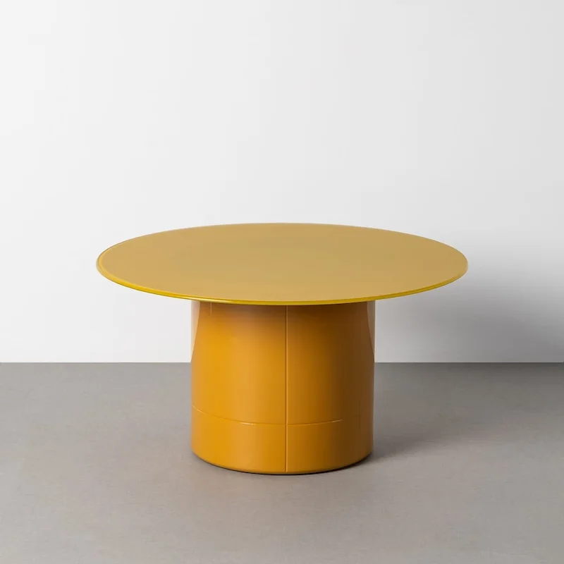 Table basse ronde Ixia, plateau en verre transparent sur pied central cylindrique jaune moutarde, vue de trois quarts